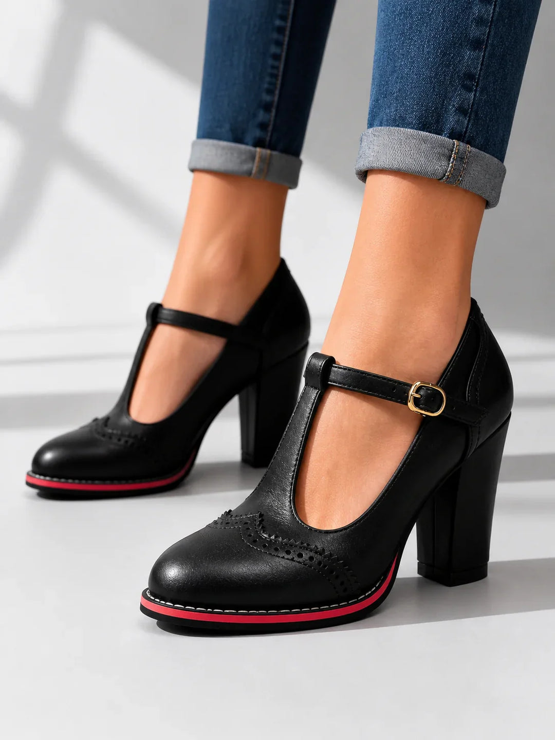 Side view of t-bar strap, buckle, brogue toe and block heel, black