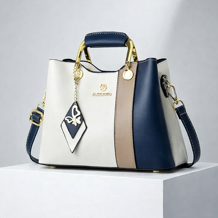 Front view of top handle, butterfly charm and crossbody strap, blue