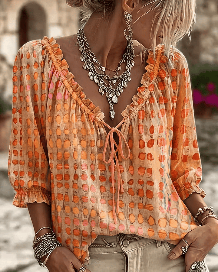 Front view of v-neckline with tie fastening, ruffle trim and puff sleeves, orange